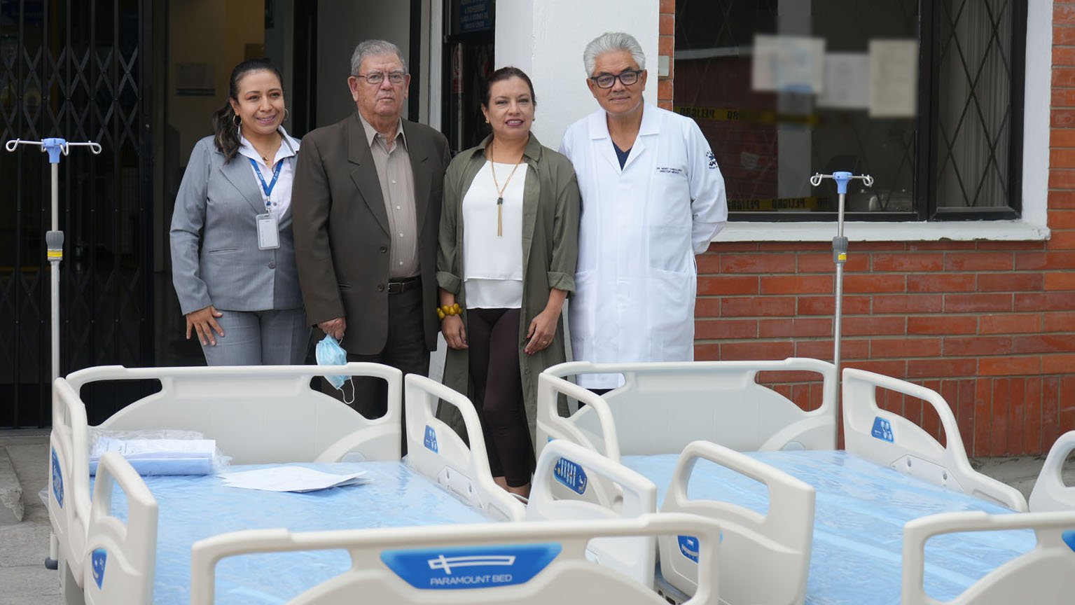 Grupo de personas posando detrás de dos camas de hospital