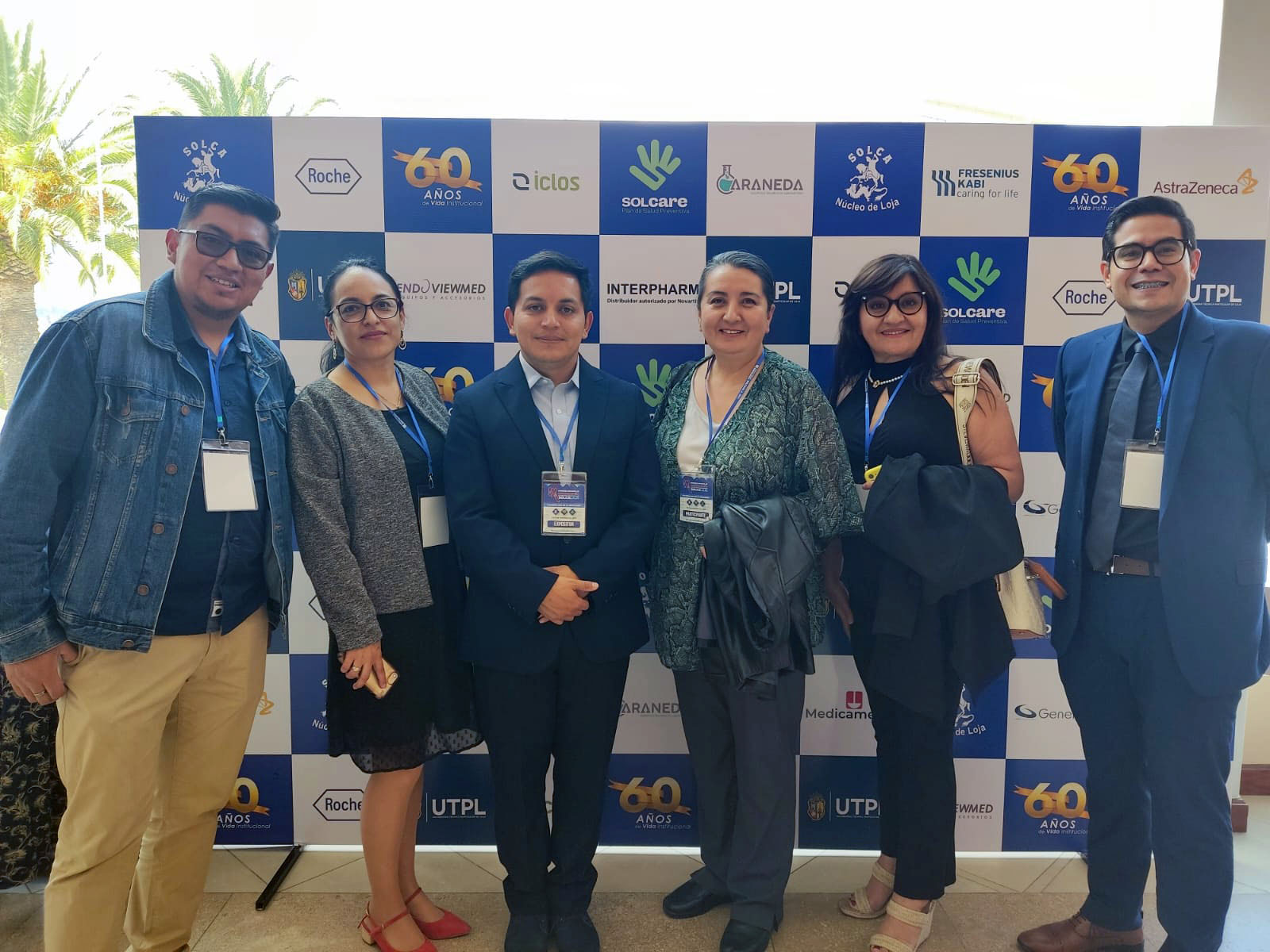 Grupo de personas posando frente a un fondo ajedrezado